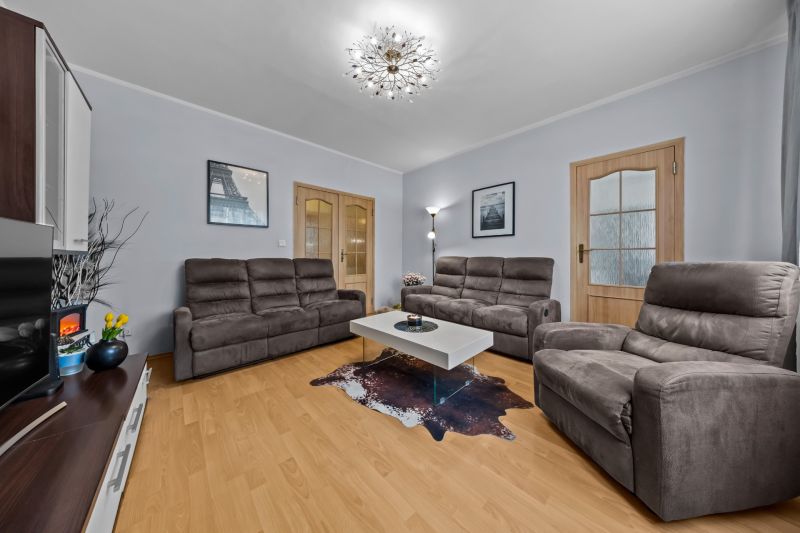 Living room with a comfortable sofa, table, and wooden decor flooring in a 3-room apartment.
