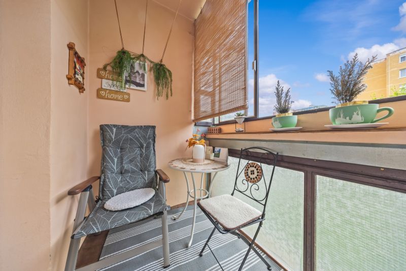 A furnished balcony in a 3-room apartment with comfortable chairs, a table, and decorations.