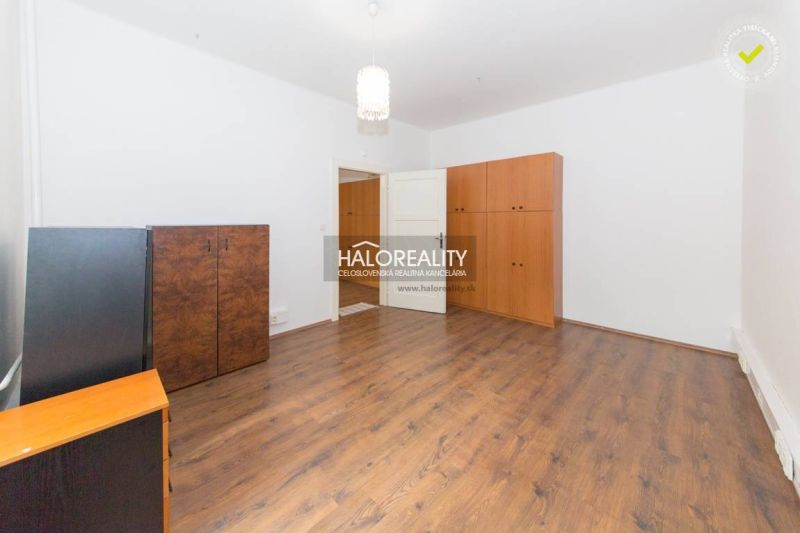 A spacious room with wooden flooring and simple furniture in a five or more room apartment.
