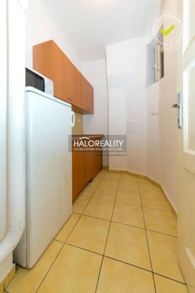 A narrow kitchen with appliances and wooden cabinets in a 5 or more room apartment.