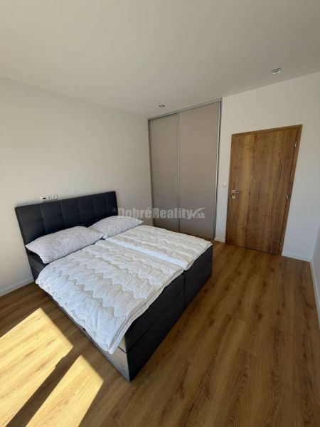 Bedroom with a bed, sliding wardrobe, and floor with wooden decor in a 2-room apartment.