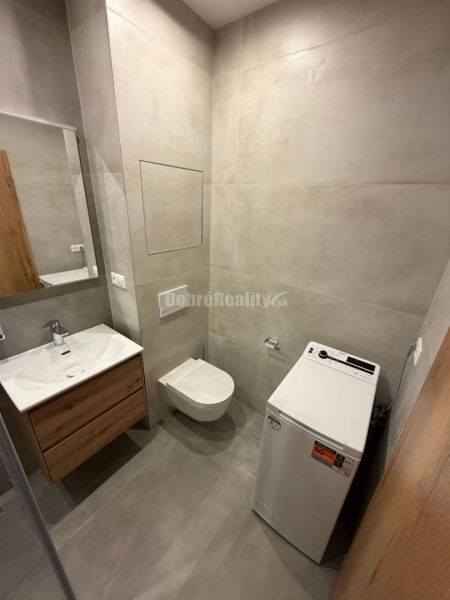 Bathroom in a 2-room apartment with a washing machine, wall-mounted toilet, and sink.