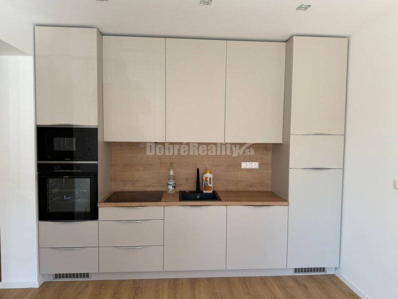 Kitchen in a 2-room apartment with white cabinets and a wood-patterned floor.
