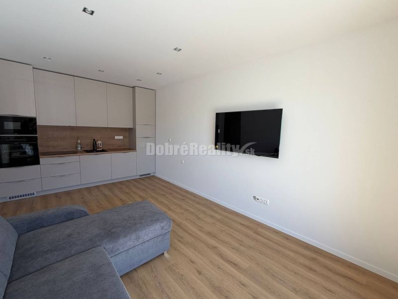 Living room in a two-room apartment with a corner sofa and kitchen, floor with wood decor.