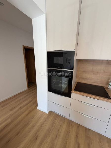 Kitchen area in a 2-room apartment with wood-patterned flooring and built-in appliances.