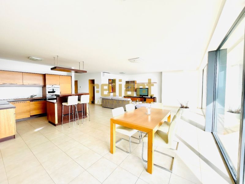 A bright kitchen with a dining table and large windows in a 4-room apartment.