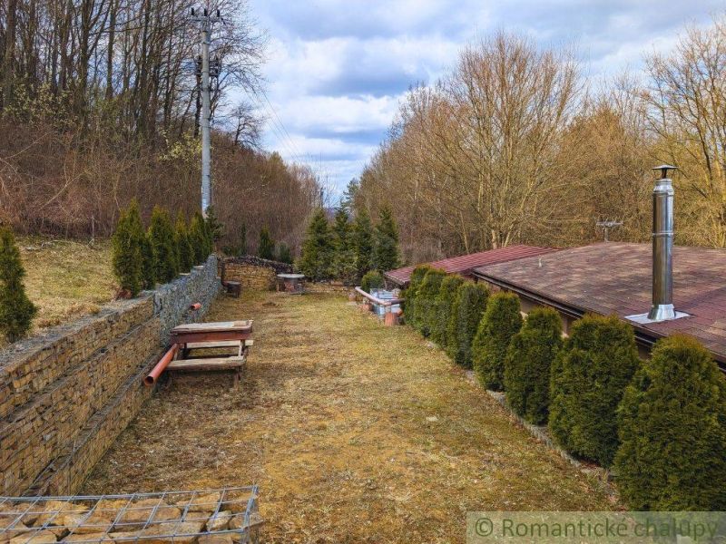 A garden with a terrace around the cottage in Kvakovce, surrounded by trees and shrubs.