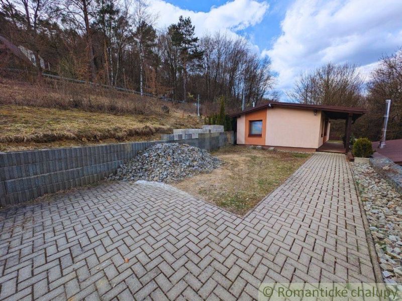A cottage in Kvakovce near the forest with a path and a pile of gravel.