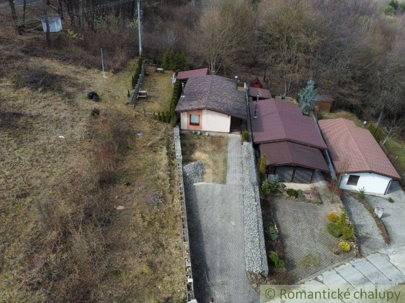 The exterior of the cottage in Kvakovce with the surrounding nature and a paved yard.