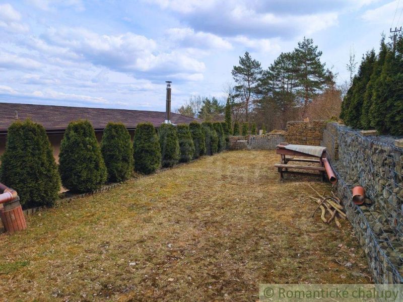 A garden at the cottage in Kvakovce with conifers and stone walls.