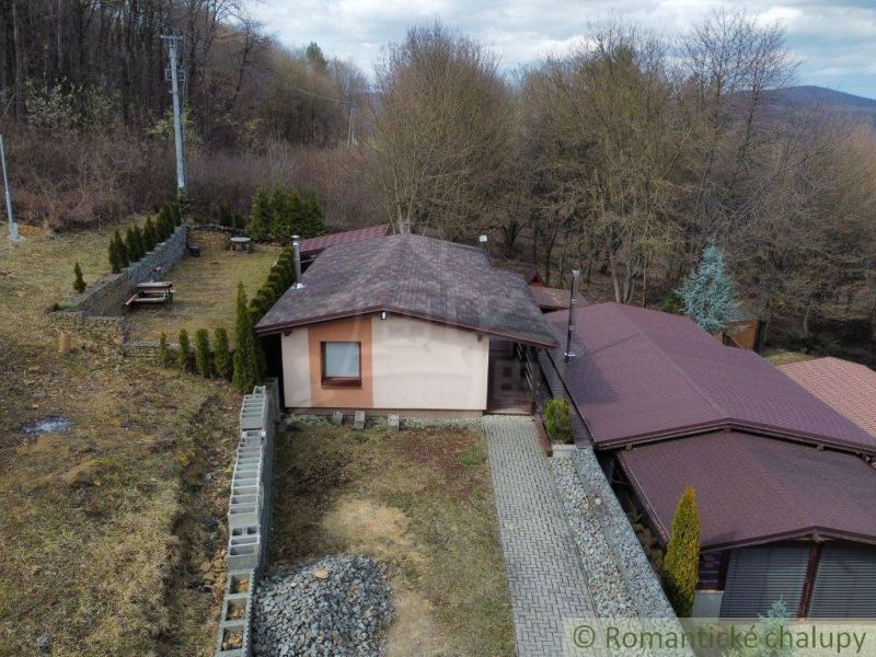 A cottage in Kvakovce surrounded by greenery near the forest with a manicured lawn and a road.