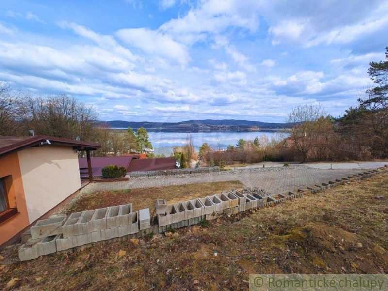 The view from the cottage in Kvakovce of the lake, surrounded by trees and a blue sky.