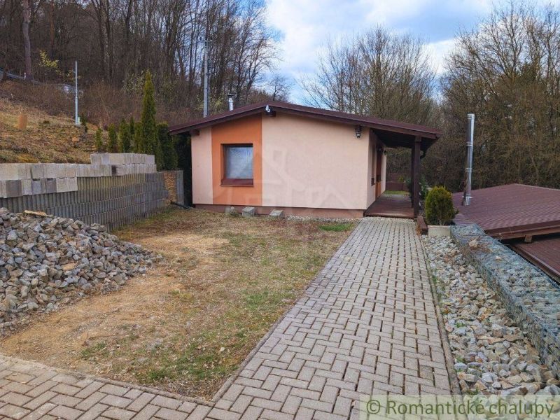 A cottage in Kvakovce surrounded by nature with a paved walkway and surrounding trees.