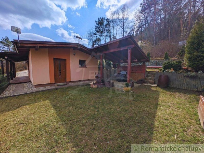 A cottage in Kvakovce with a lawn and a gazebo, bordered by trees and a forest backdrop.