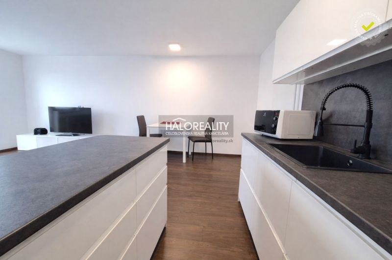 A kitchen in a 2-room apartment with a wooden decor floor and modern equipment.