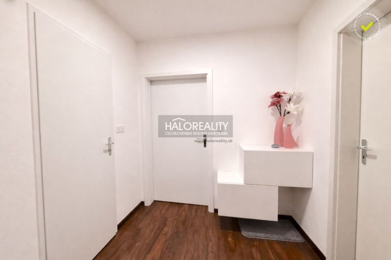 Entrance hallway in a 2-room apartment with wood-patterned flooring and white furniture.
