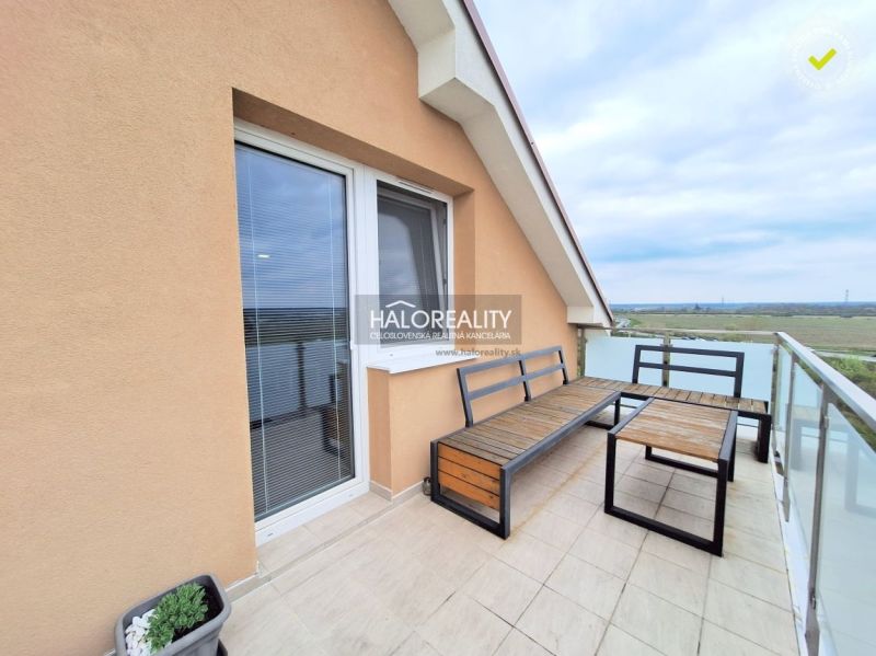 A balcony with wooden furniture in a two-room apartment with a view of nature in Pezinok.