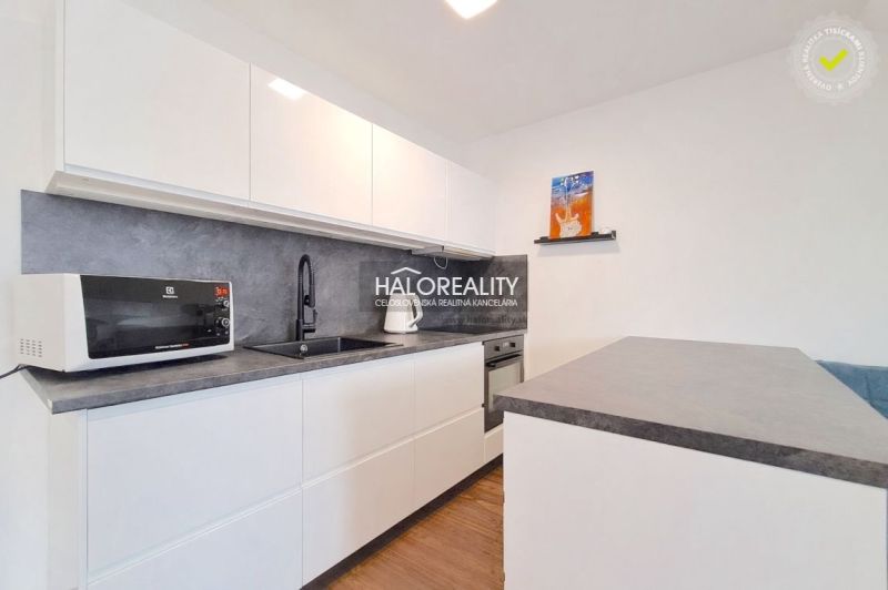 A kitchen in a 2-room apartment with a white kitchen unit and a floor with a wood decor.