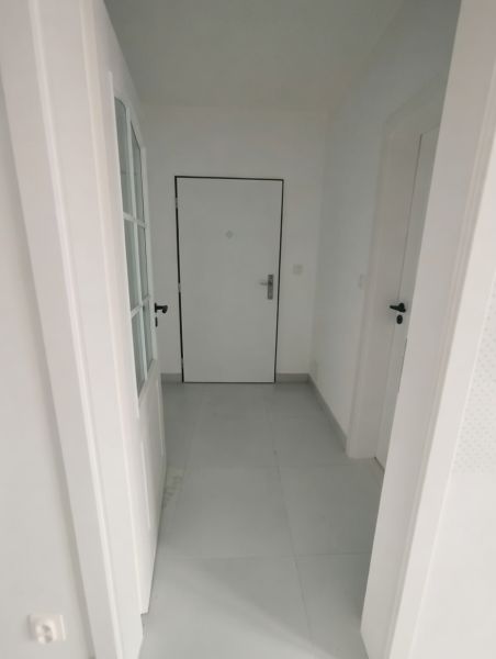 Hallway of a 2-room apartment with white doors and light flooring.