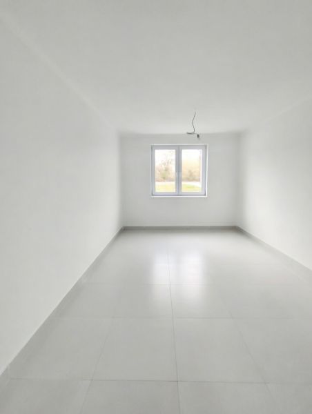A spacious bright room with a window in a 2-room apartment, white tiles.