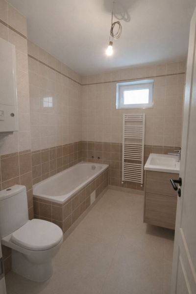 Bathroom in a 2-room apartment with a bathtub and tiles in light tones.