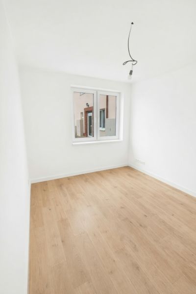 A room with a wooden floor decor and a window in a 2-room apartment.