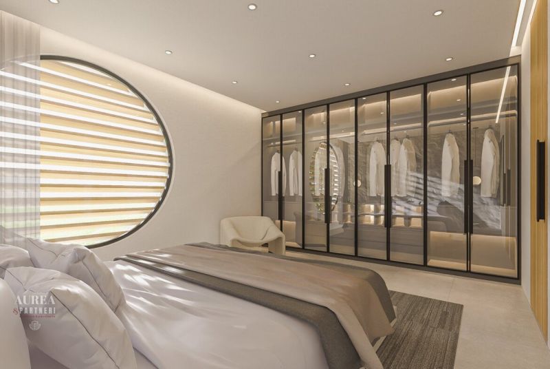 A bedroom in a villa with a large window, a wardrobe with glass doors, and a bed.