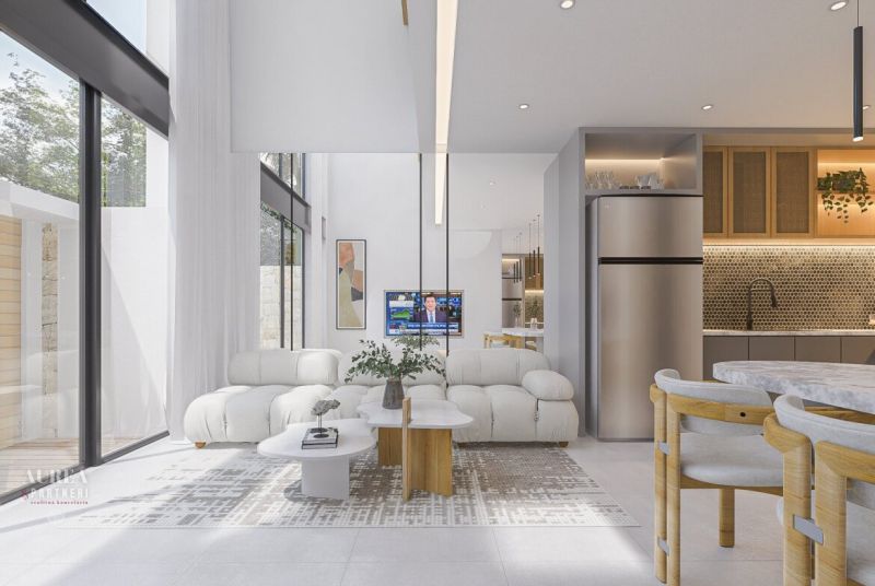 Bright living room in a villa with a sofa, television, and kitchen area with a plant.