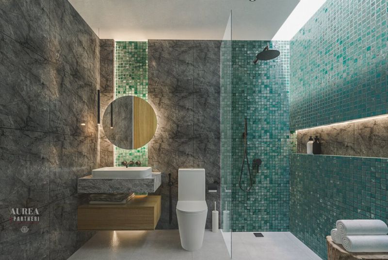 A bathroom in a villa with a mosaic green wall and dark marble tiles.