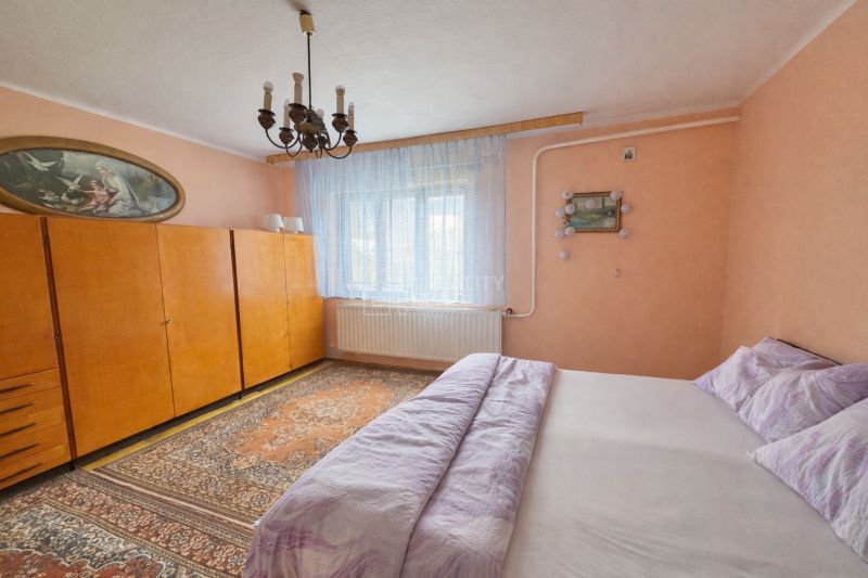 Bedroom with a bed, wardrobe, and chandelier in a family house.