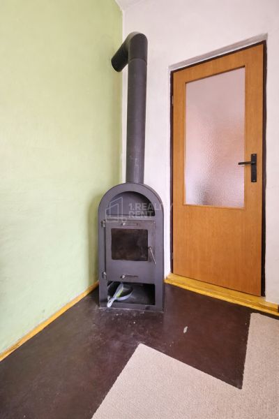 Wood-burning stove near wooden doors, gray floor with floor decor.