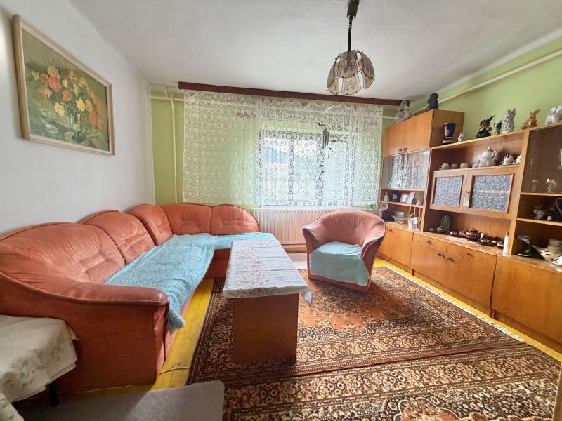 Living room of a family house with an orange sofa and wooden furniture.