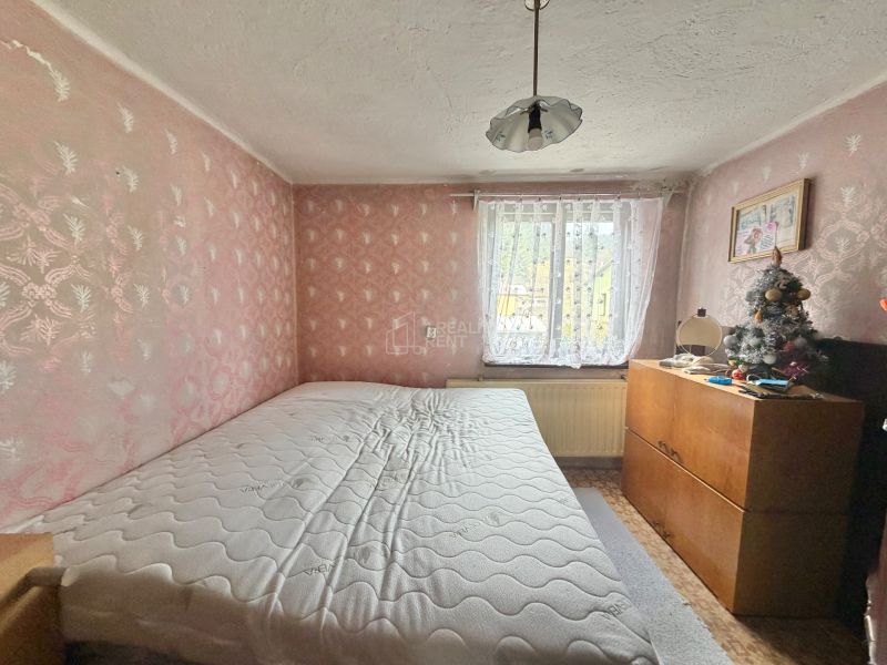 A bedroom in a family house with pink walls, a comfortable bed, and a dresser.