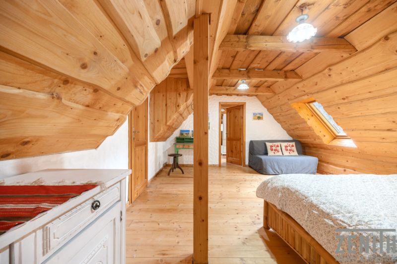 Attic in a family house with wooden wall and ceiling decor, bed, couch, furniture.
