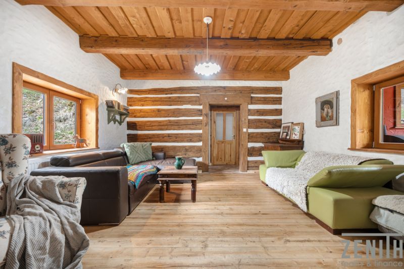 Living room in a family house with sofas, wooden beams, and a floor with a wooden decor.