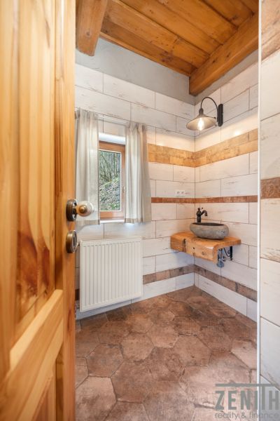 A bathroom in a family house with a stone sink and a wooden ceiling.
