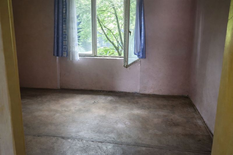 A room in a family house, an older floor, an open plastic window with blue curtains.