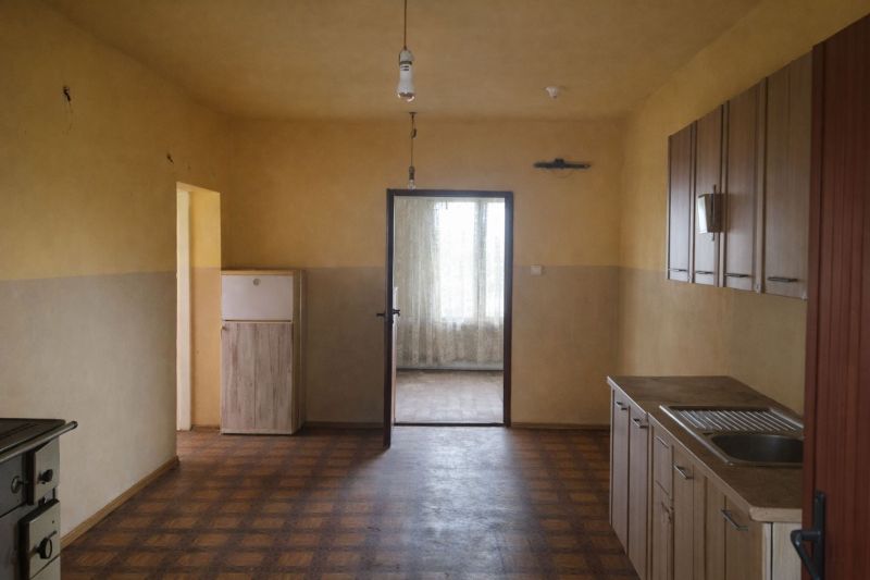 A kitchen in a family house with a wooden decor floor and a simple countertop.