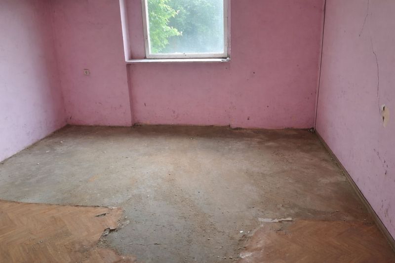 A room in a family house with pink walls and a wooden decor floor.