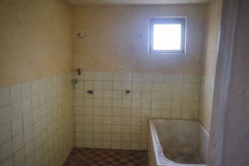 An older bathroom in a family house with a bathtub and tiled walls.