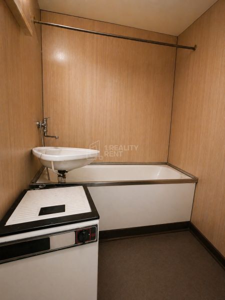 A bathroom with a bathtub and a sink in a 2-room apartment.