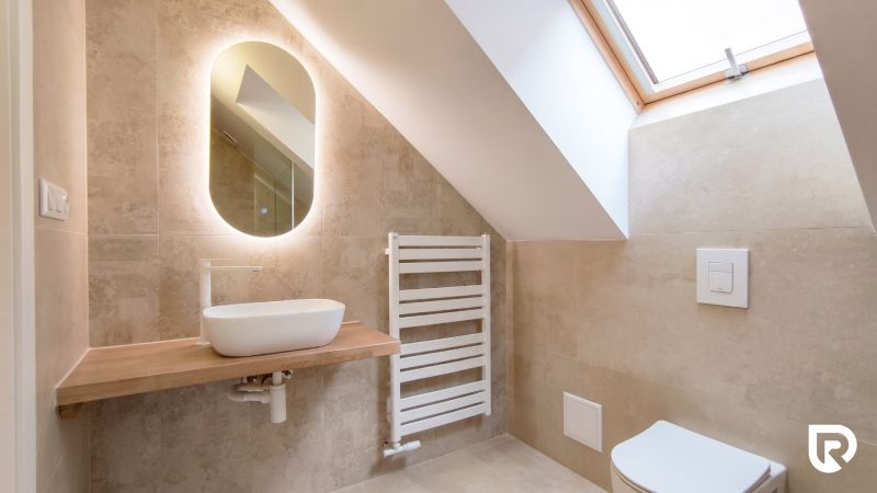 A bathroom with an oval mirror, sink, radiator, and slanted ceiling.