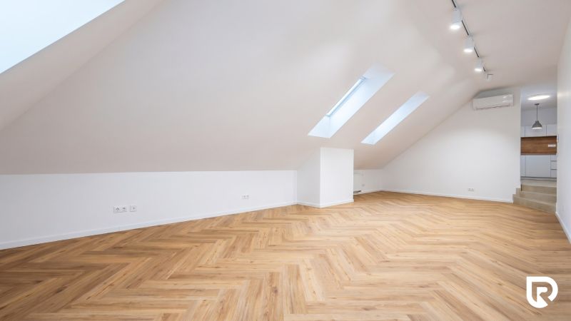 Attic space with a wooden decor floor and lighting suitable for offices.