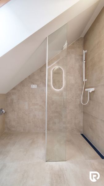 Shower enclosure with a glass wall and a showerhead on a tiled wall.