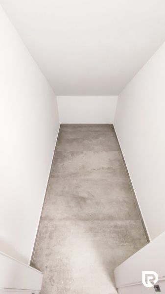 A narrow office space with white walls and a gray floor.