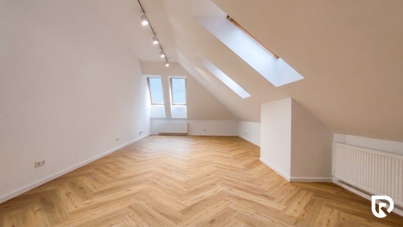 Loft interior of offices with large skylights and wood-patterned flooring.