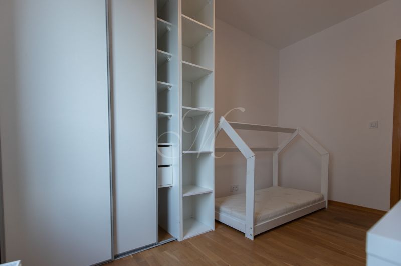 Children's room with a house-shaped bed, wardrobe, and wooden decor flooring.