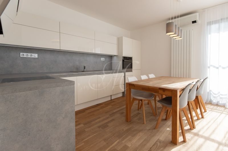 A kitchen in a 3-room apartment with a wooden decor floor and a dining table.