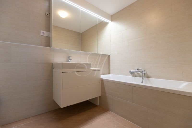 A bathroom with a bathtub and a sink in a 3-room apartment, light tiles on the walls.