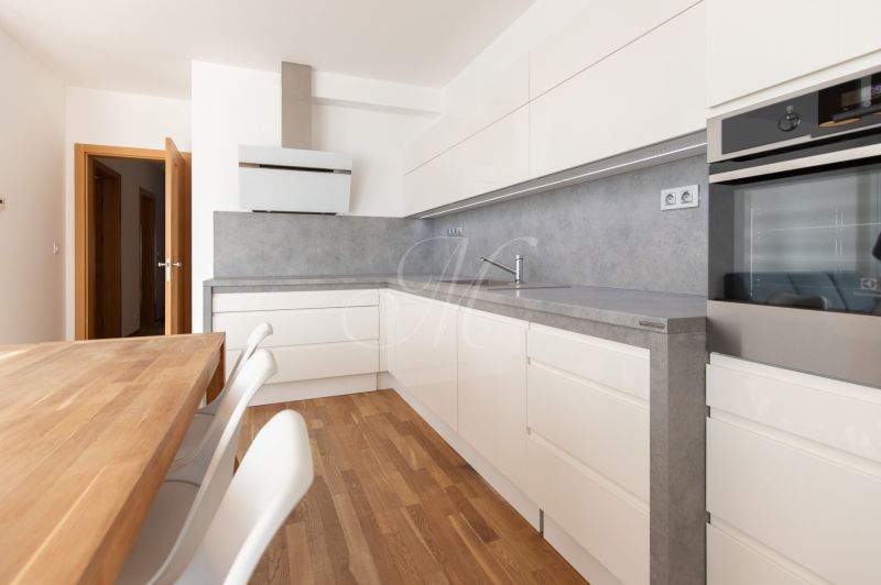 A kitchen in a 3-room apartment with a wood-decor floor and built-in appliances.